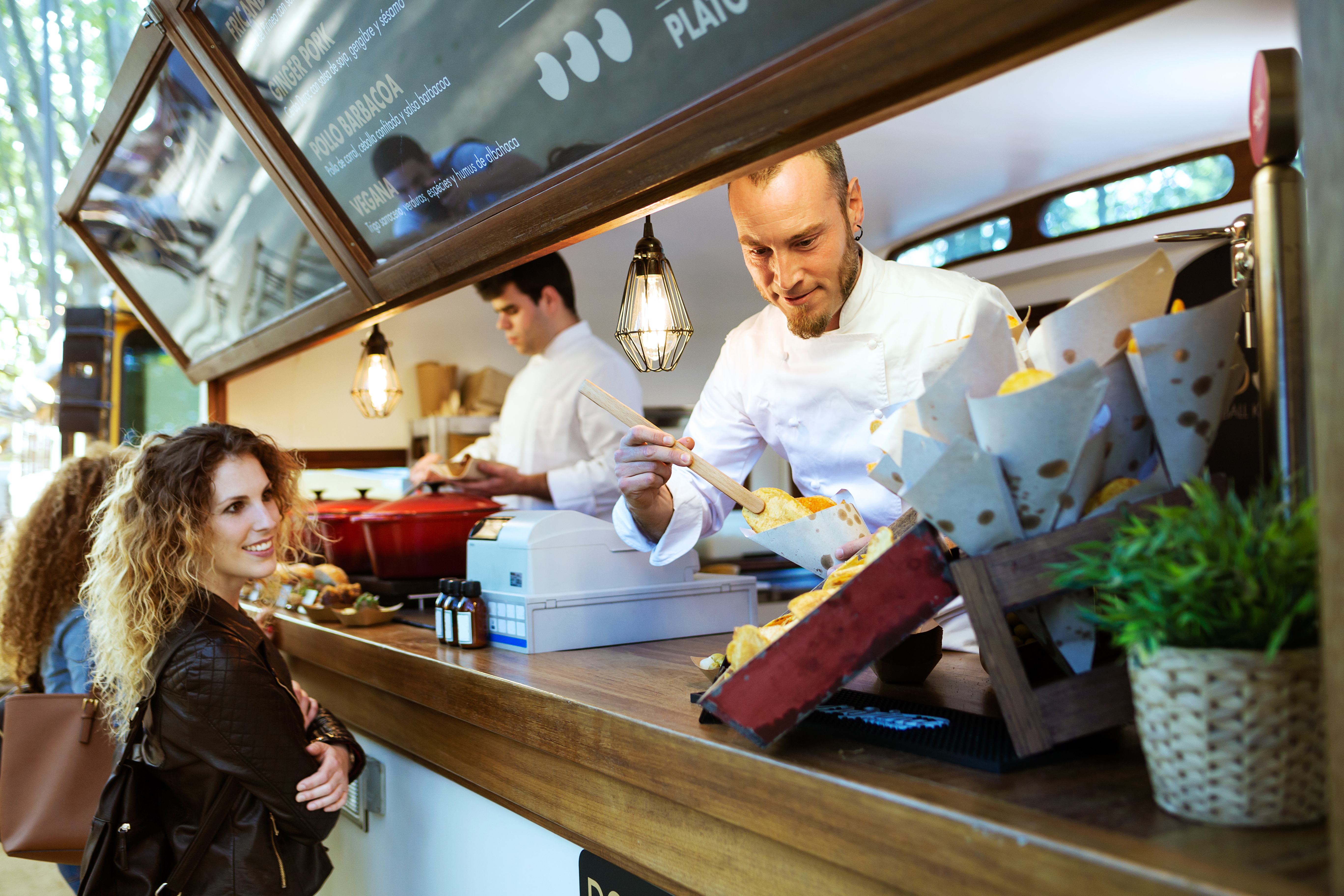 A man severing barbecue potatoes to a smiling woman